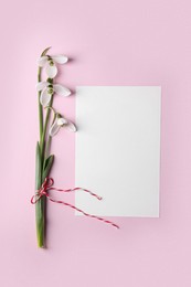 Photo of Beautiful snowdrops and paper card on pink background, flat lay. Space for text