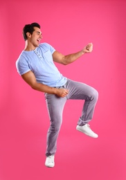 Photo of Handsome young man dancing on pink background