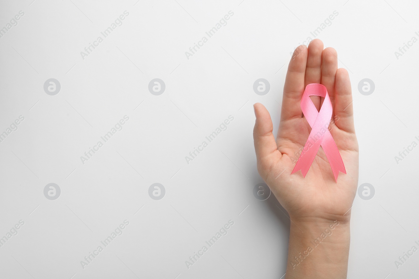 Photo of Woman holding pink ribbon on white background, top view with space for text. Breast cancer awareness concept