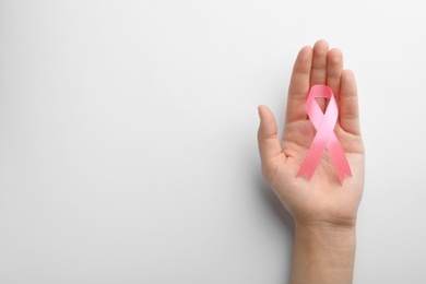 Woman holding pink ribbon on white background, top view with space for text. Breast cancer awareness concept