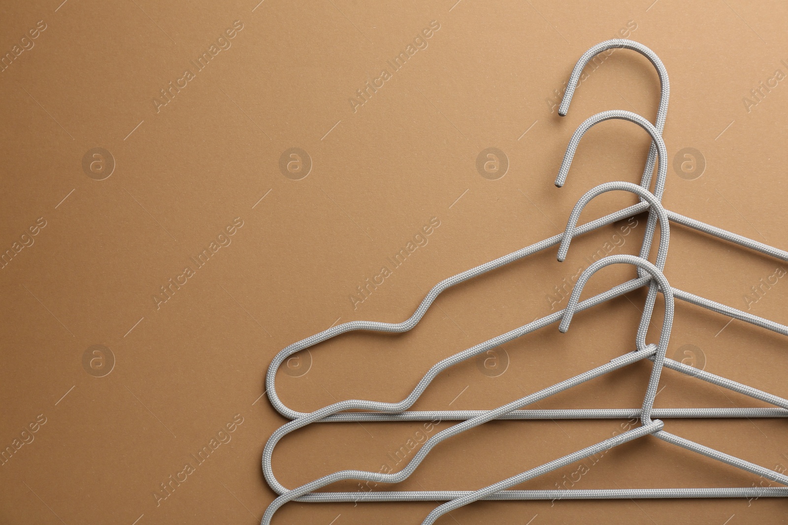 Photo of Empty hangers on brown background, top view. Space for text