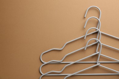 Empty hangers on brown background, top view. Space for text