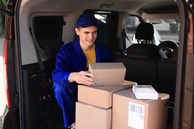 Photo of Courier checking packages in van. Delivery service