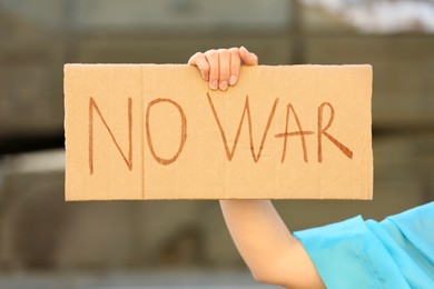 Photo of Woman holding poster with words No War outdoors, closeup