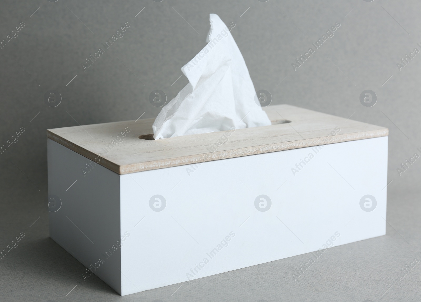 Photo of Holder with paper tissues on grey background