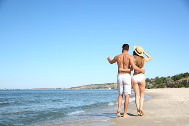 Photo of Woman in bikini and her boyfriend on beach, back view with space for text. Lovely couple