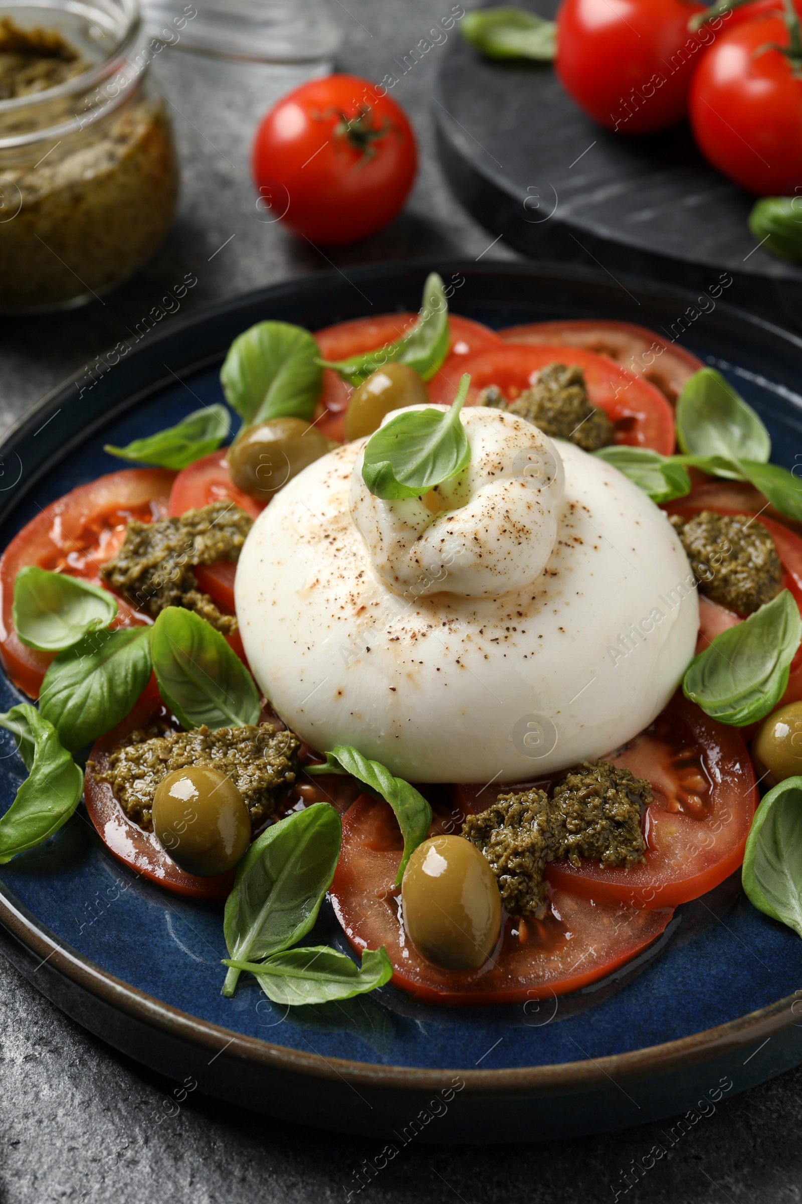 Photo of Delicious burrata salad served on grey table, closeup