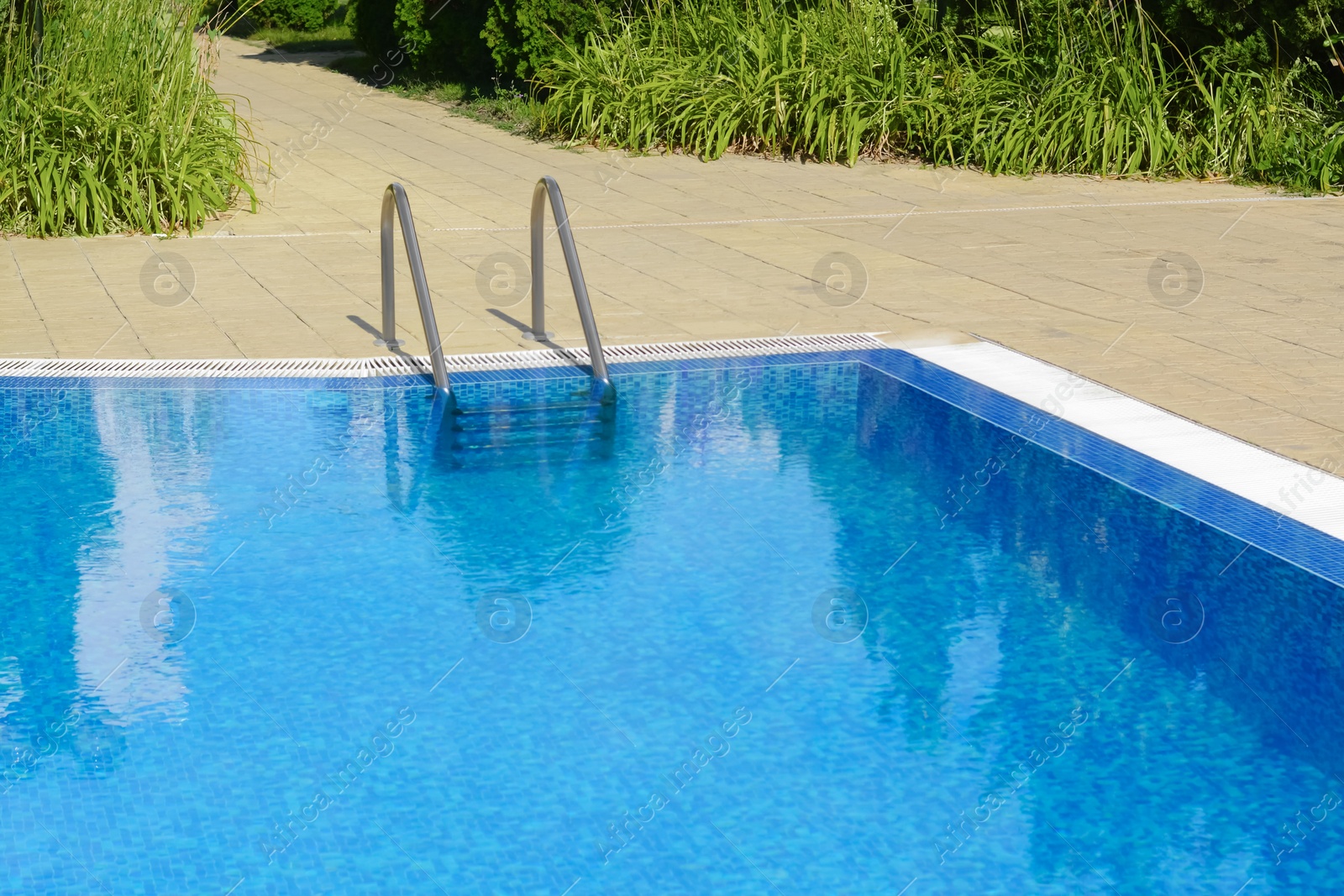 Photo of Outdoor swimming pool with ladder and handrails on sunny day