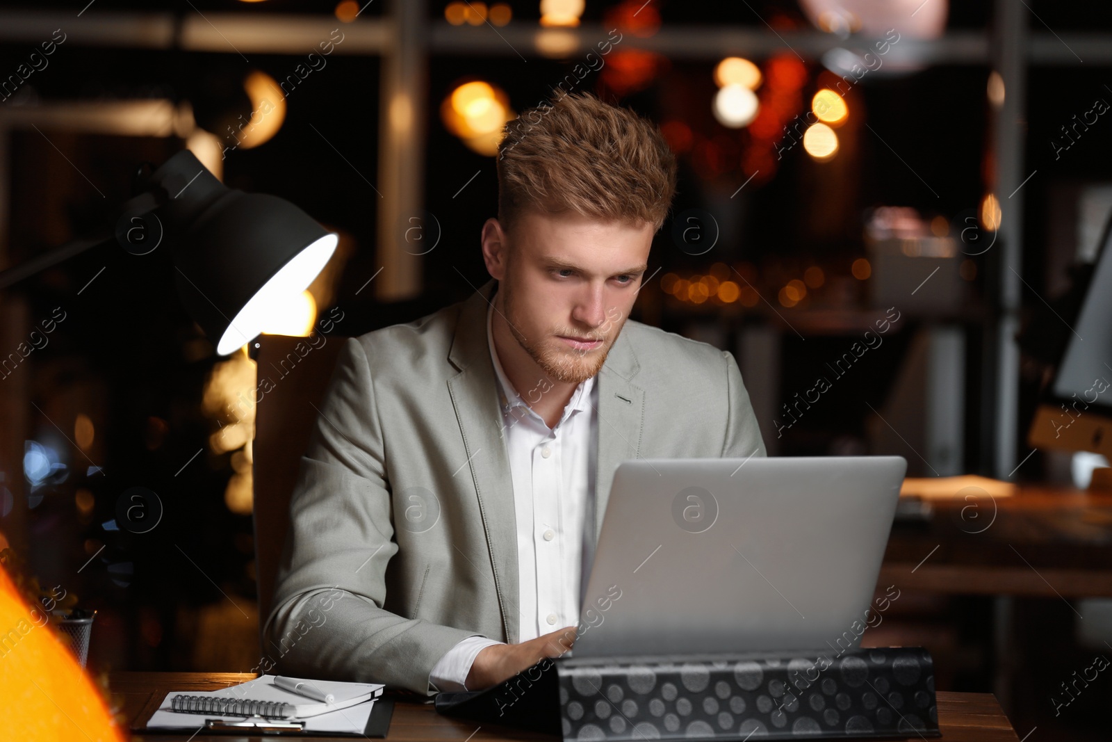 Photo of Young man working in office at night