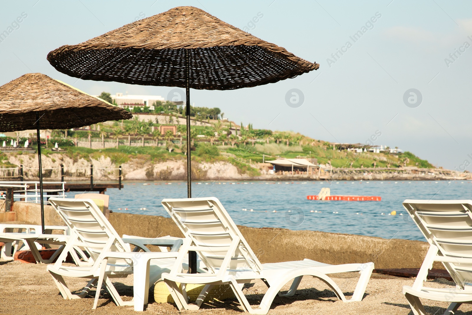 Photo of Lounge chairs and beach umbrellas on sea shore