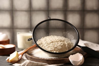 Photo of Making dough. Flour in sieve, spoon and butter on table, closeup