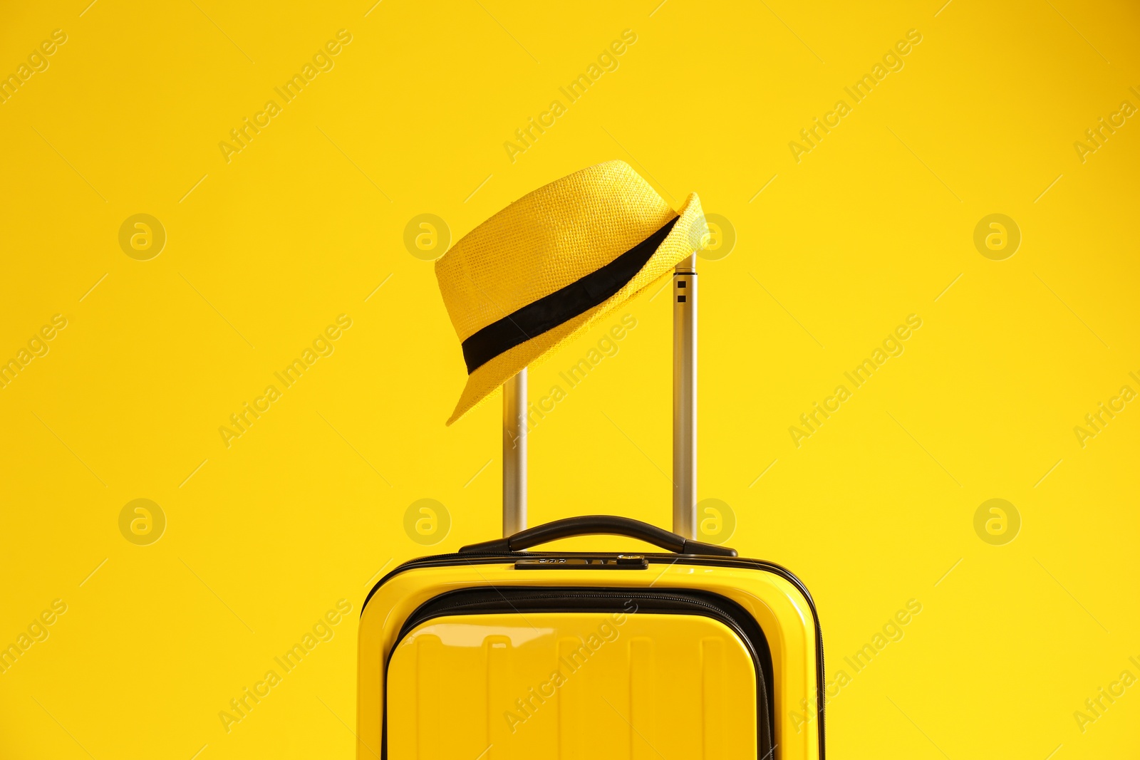 Photo of Bright suitcase with hat on color background