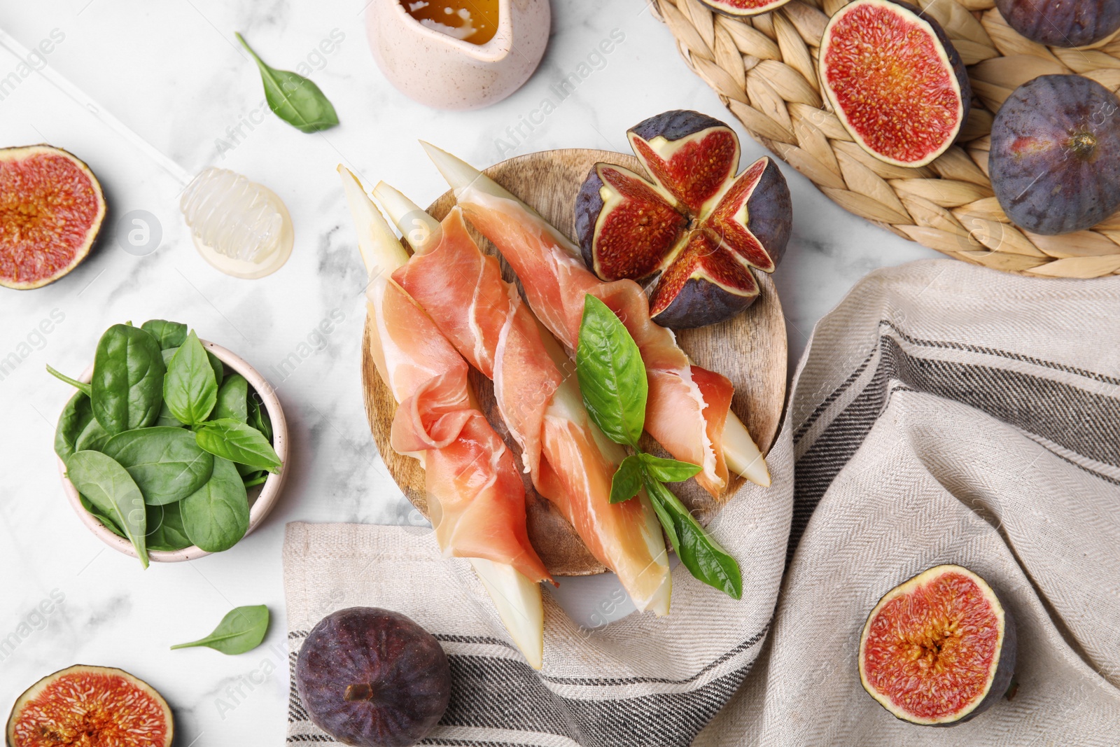 Photo of Tasty melon, jamon and figs served on white marble table, flat lay