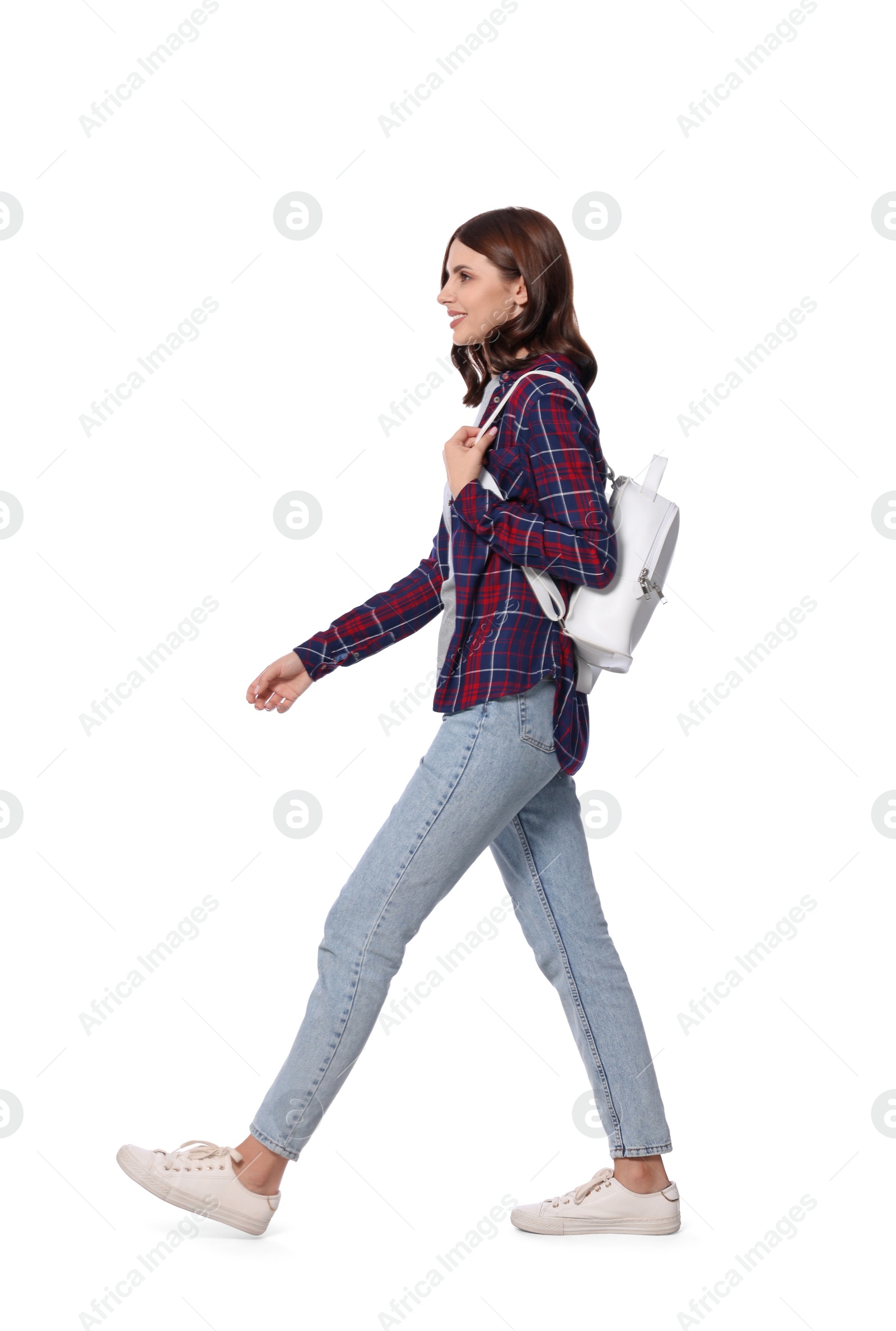 Photo of Happy young woman with stylish backpack walking against white background