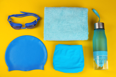 Flat lay composition with swimming accessories on yellow background