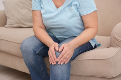 Photo of Senior woman suffering from knee pain at home, closeup