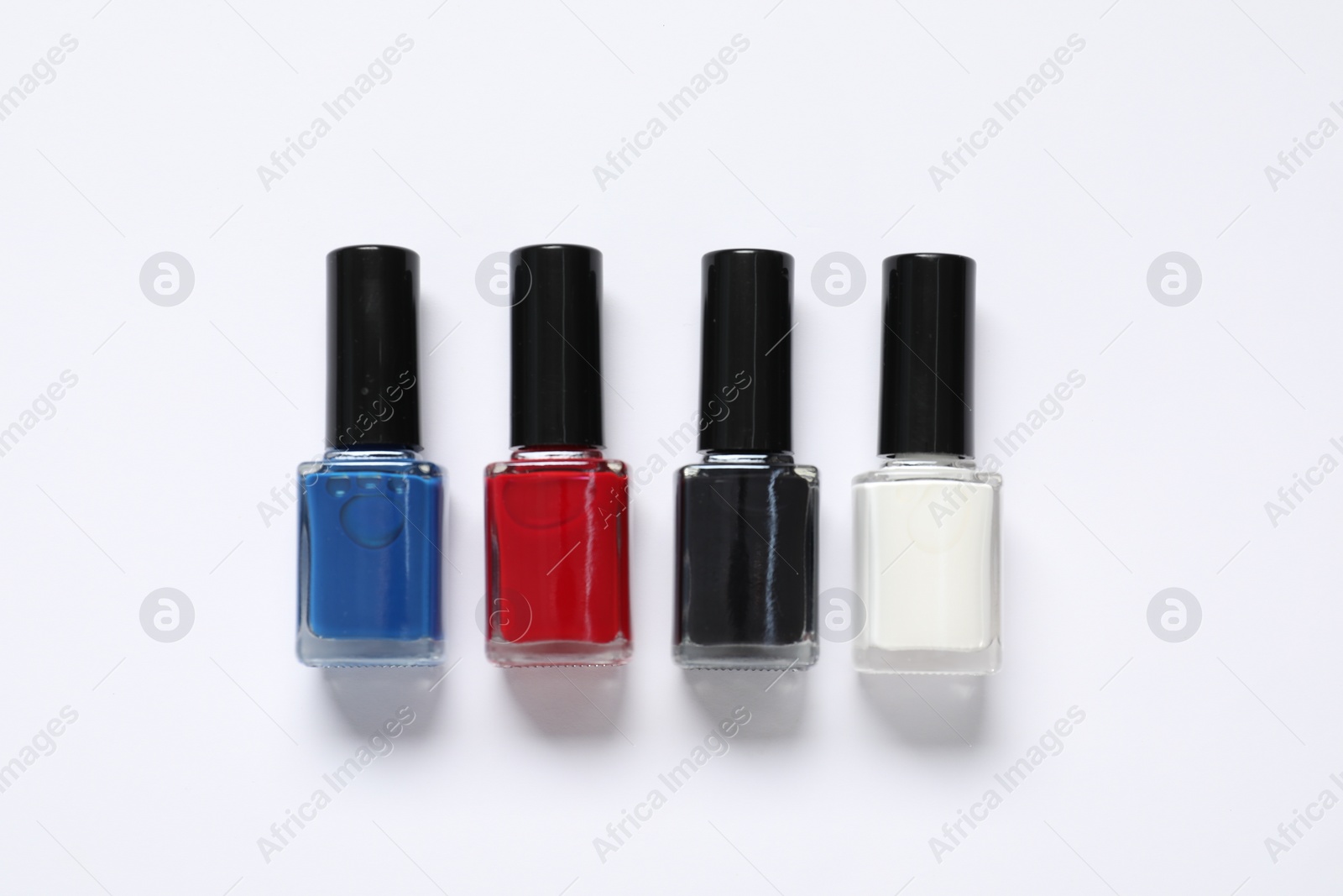 Photo of Nail polishes on white background, flat lay