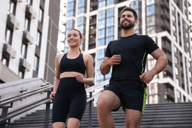 Photo of Healthy lifestyle. Happy couple running on steps outdoors, low angle view