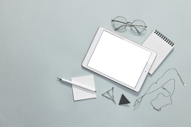 Photo of Flat lay composition with modern tablet on light grey background. Space for text