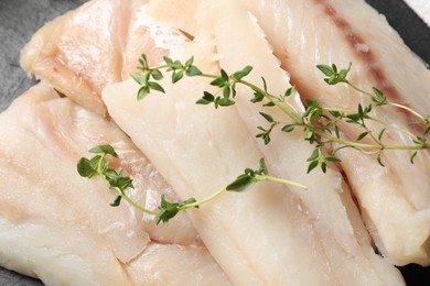 Photo of Pieces of raw cod fish and microgreens on table, closeup