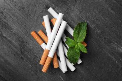 Photo of Menthol cigarettes and mint on grey table, flat lay