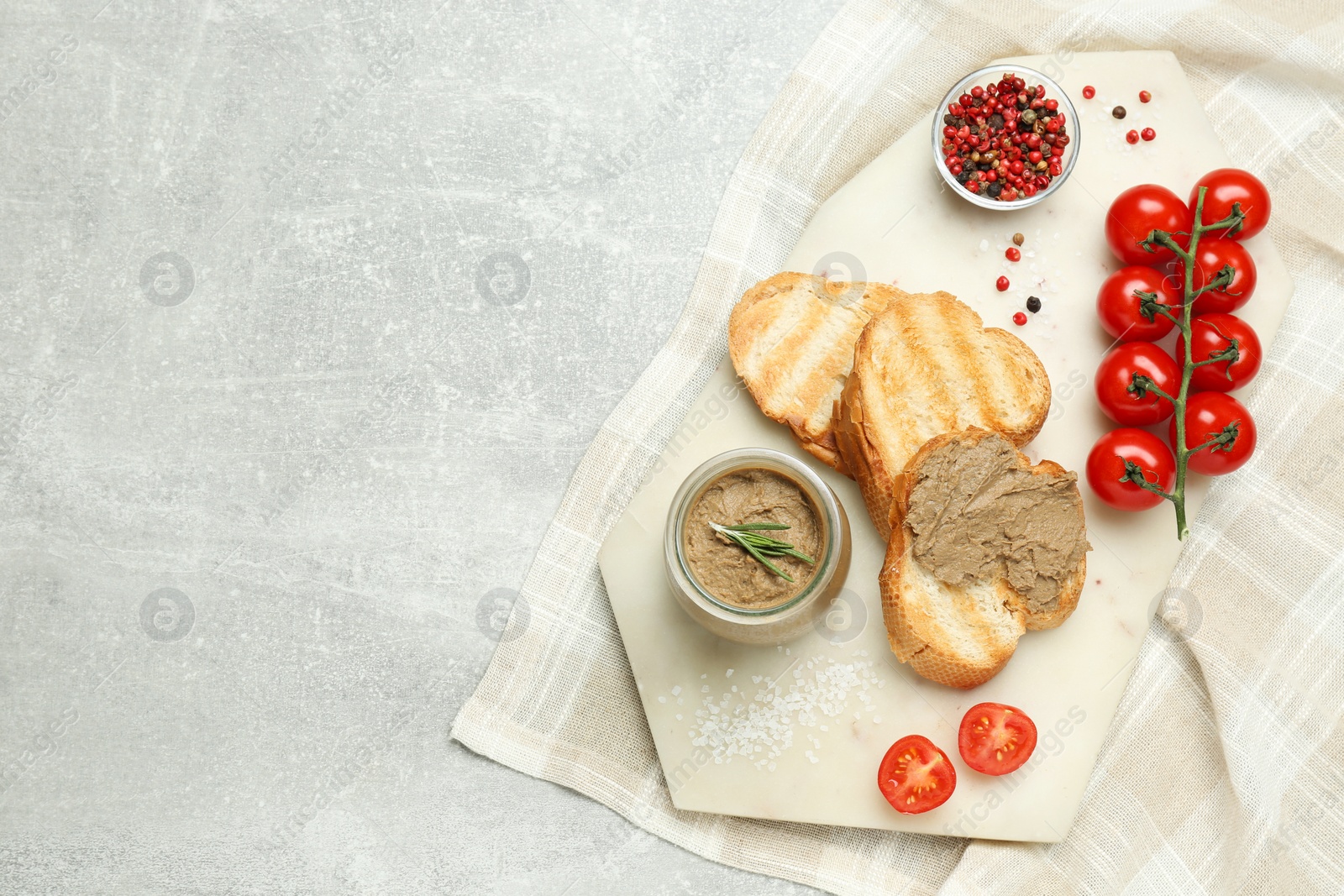 Photo of Tasty liver pate, bread and tomatoes on light grey table, top view. Space for text