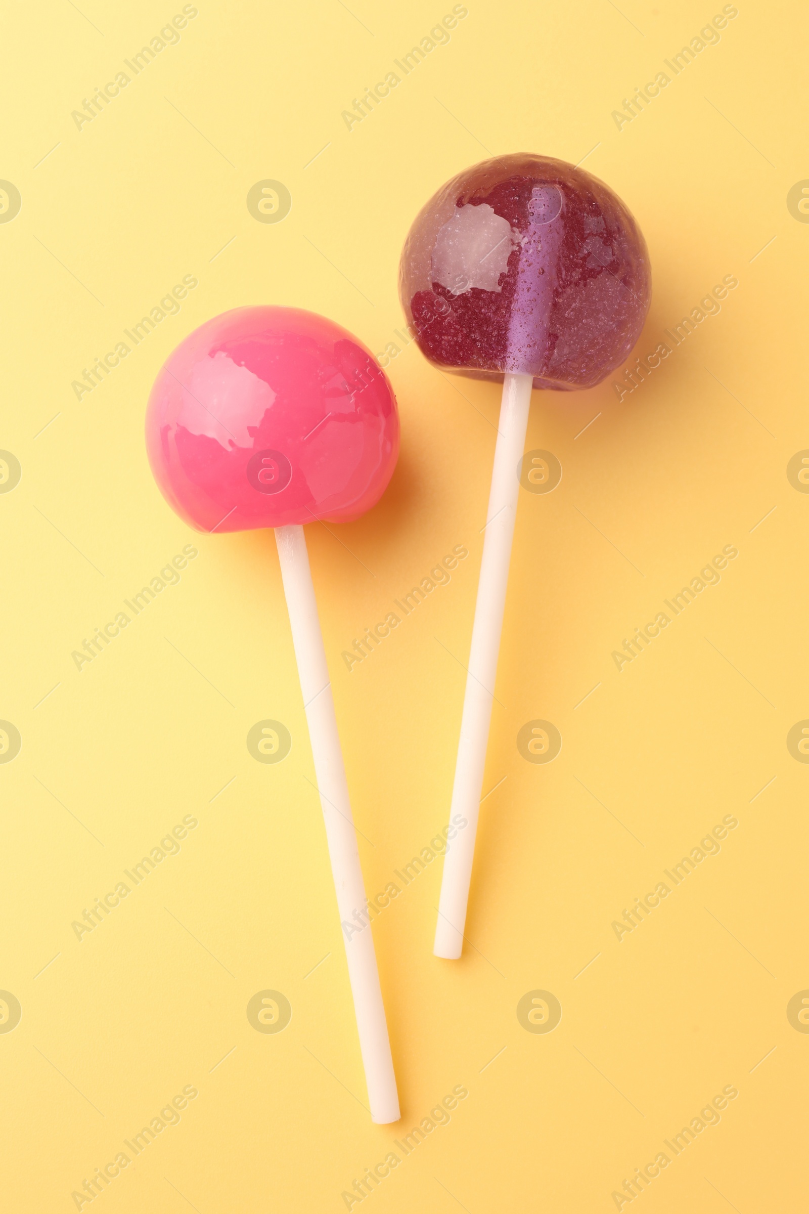 Photo of Tasty lollipops on yellow background, flat lay