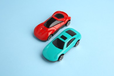 Photo of Two bright cars on light blue background, above view. Children`s toys