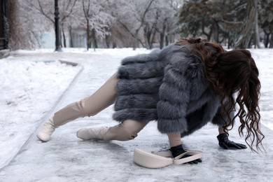 Photo of Young woman fallen on slippery icy pavement in park