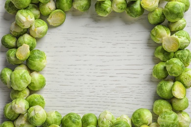 Photo of Frame made with Brussels sprouts on wooden background, top view. Space for text