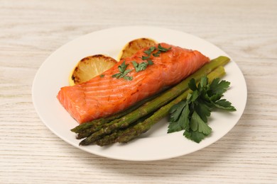 Photo of Tasty grilled salmon with asparagus and lemon on white wooden table, closeup