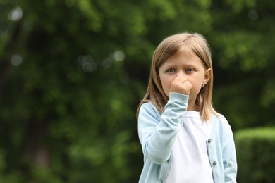 Photo of Little girl suffering from seasonal spring allergy outdoors, space for text