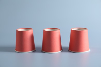 Photo of Shell game. Three red cups on light blue background