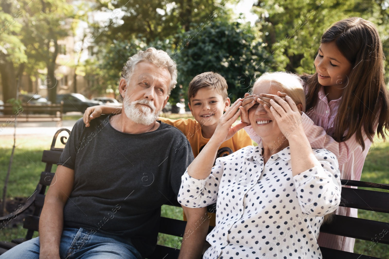 Photo of Happy grandparents with little children having fun together in park