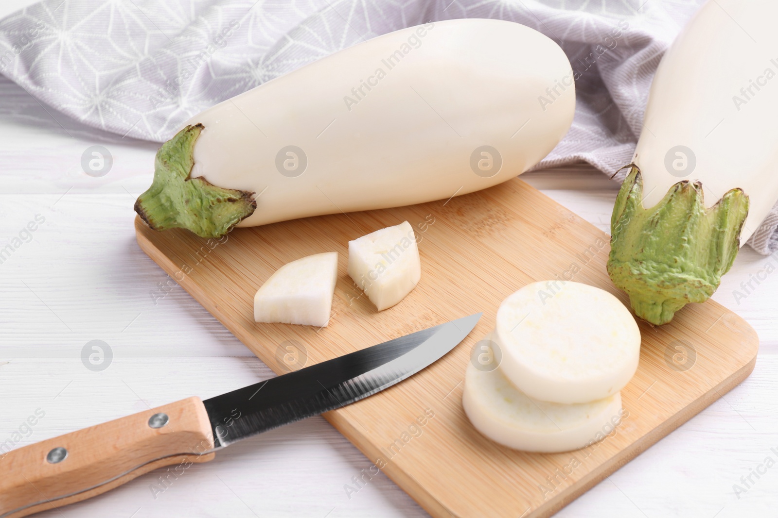 Photo of Board, raw white eggplants and knife on wooden table