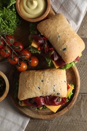 Photo of Delicious sandwiches with bresaola, cheese and lettuce served on wooden table, flat lay