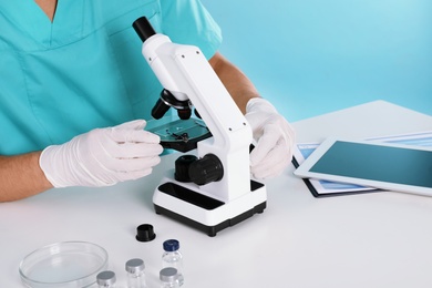 Photo of Male doctor using microscope at table, closeup. Medical object