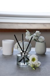 Photo of Reed diffuser, scented candle and eustoma flowers on gray marble table