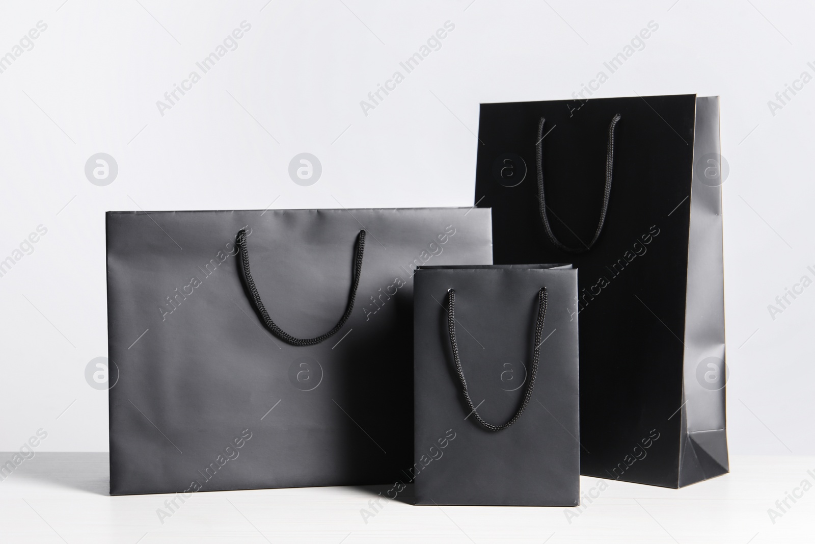 Photo of Black paper bags on white wooden table