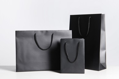 Photo of Black paper bags on white wooden table