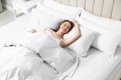 Photo of Young woman awaking in comfortable bed with silky linens