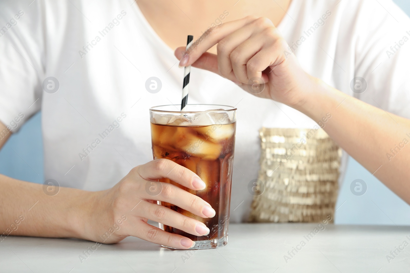 Photo of Woman with glass of tasty refreshing cola at table, closeup view