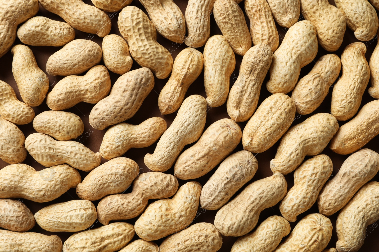 Photo of Many fresh unpeeled peanuts as background, top view