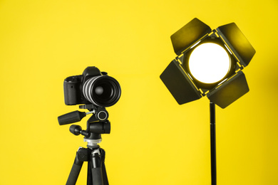 Photo of Professional video camera and lighting equipment on yellow background