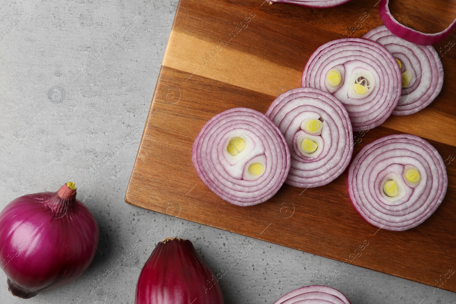 Photo of Red onion and wooden board on light grey table, flat lay