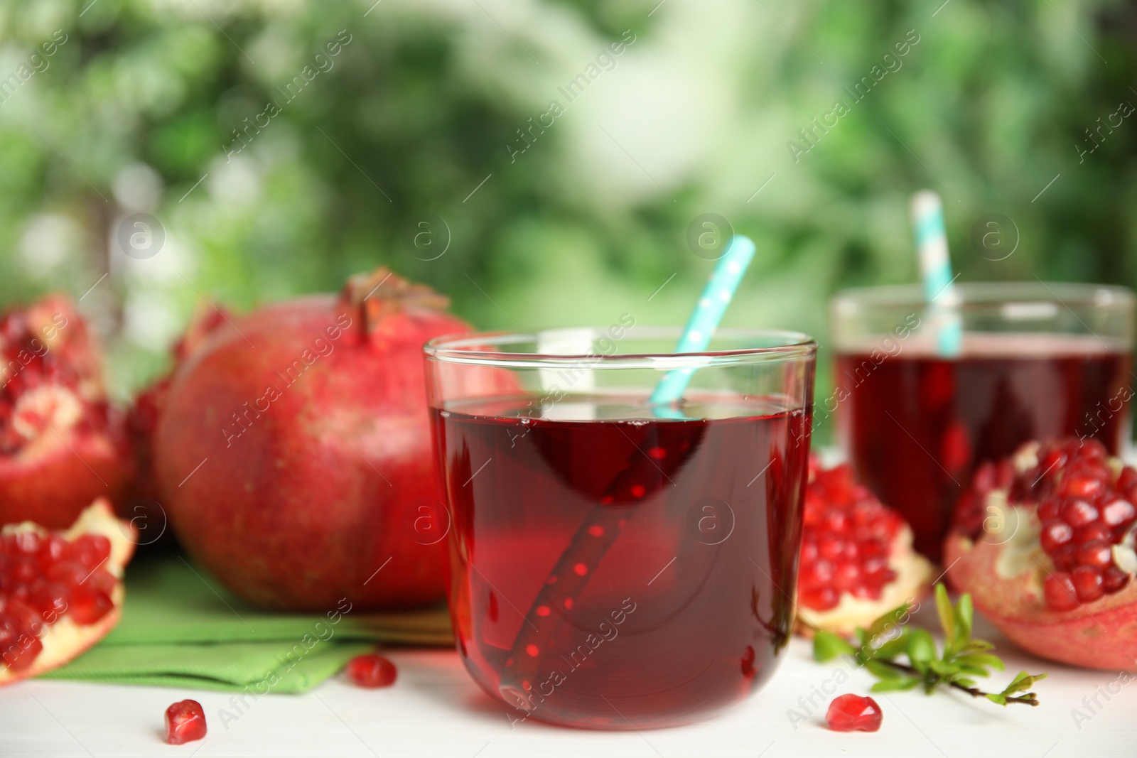 Photo of Pomegranate juice and fresh fruits on white table outdoors