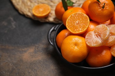 Photo of Fresh juicy tangerines on black table, space for text