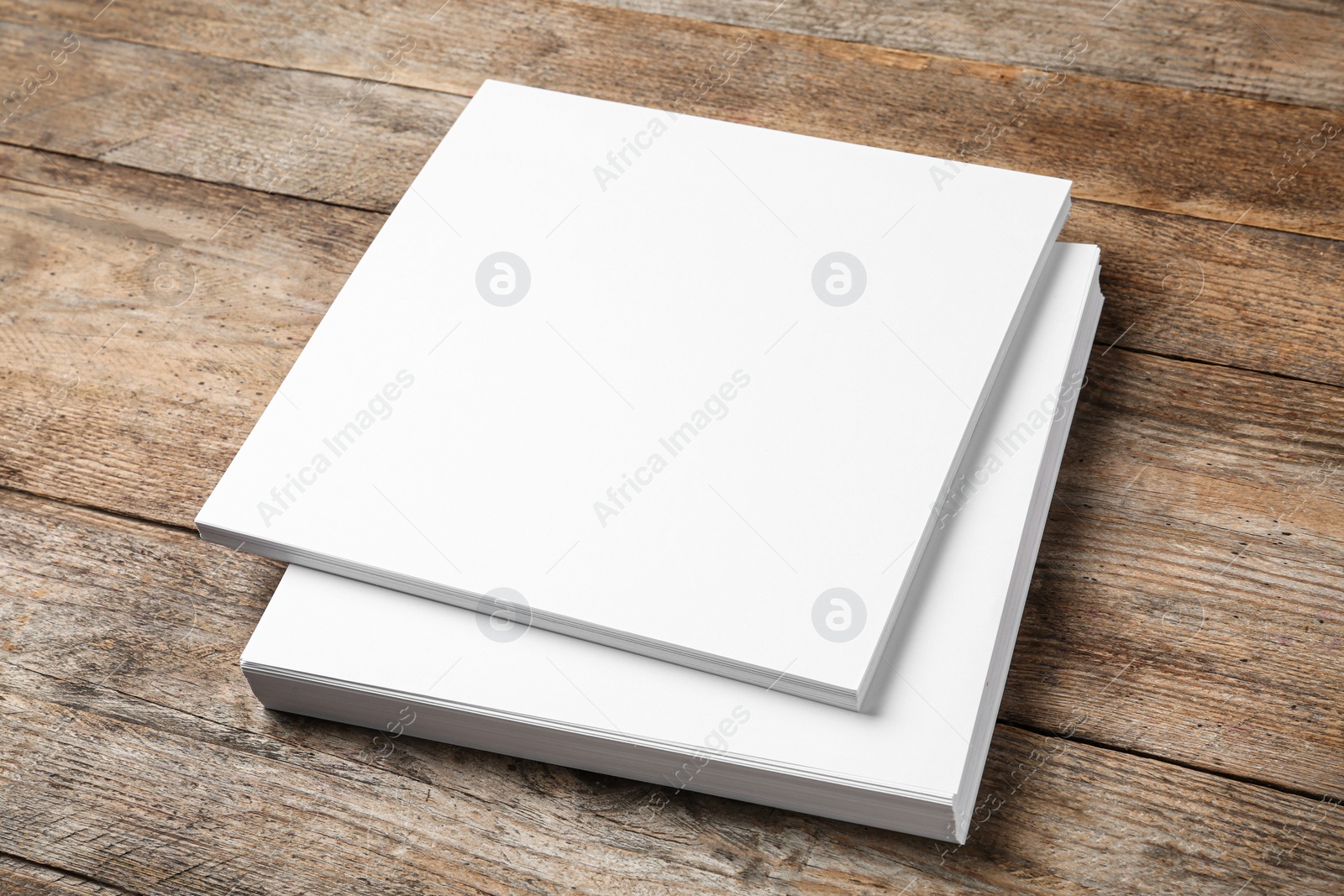 Photo of Stack of blank paper sheets for brochure on wooden background. Mock up