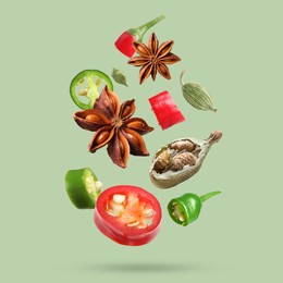 Image of Different spices falling on light green background