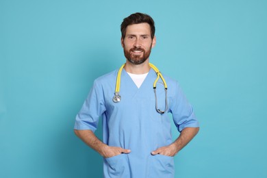 Photo of Happy doctor with stethoscope on light blue background